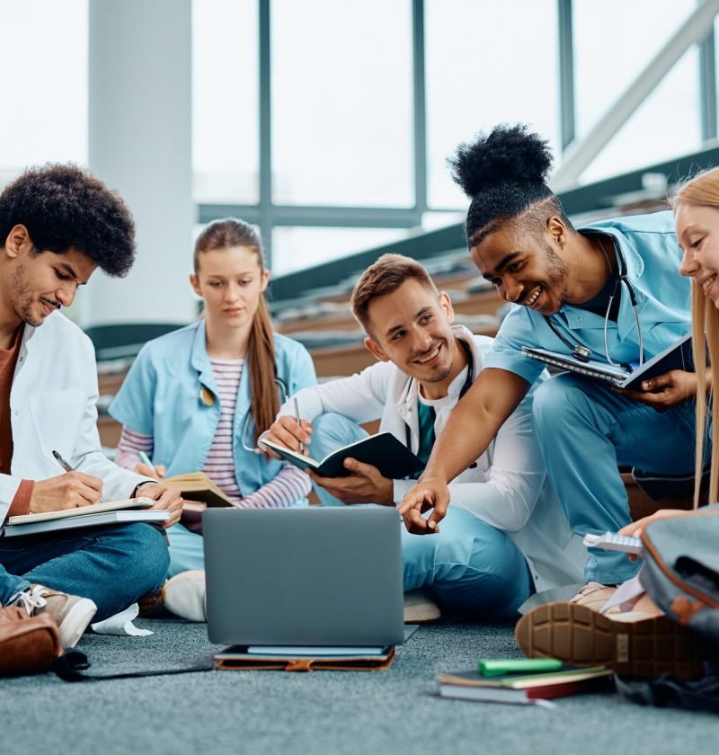 Group of happy medical students using laptop while learning in amphitheater.